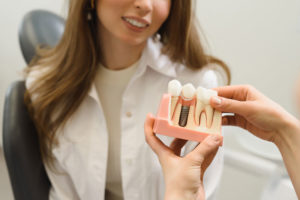 Dental Patient Getting Shown A Dental Implant Model During Her Consultation in St. Johns, MI